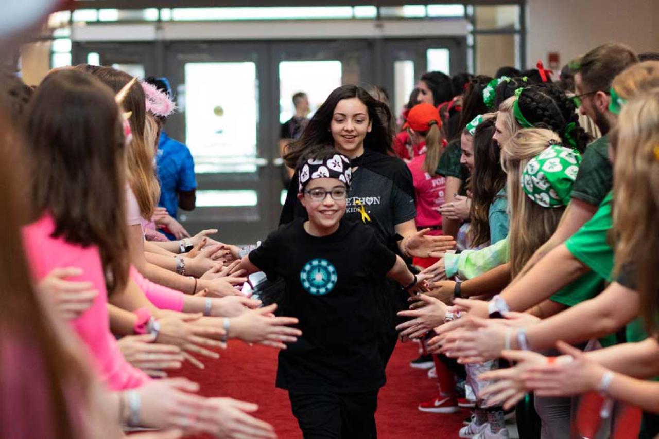 Image of child running on red carpet giving high fives