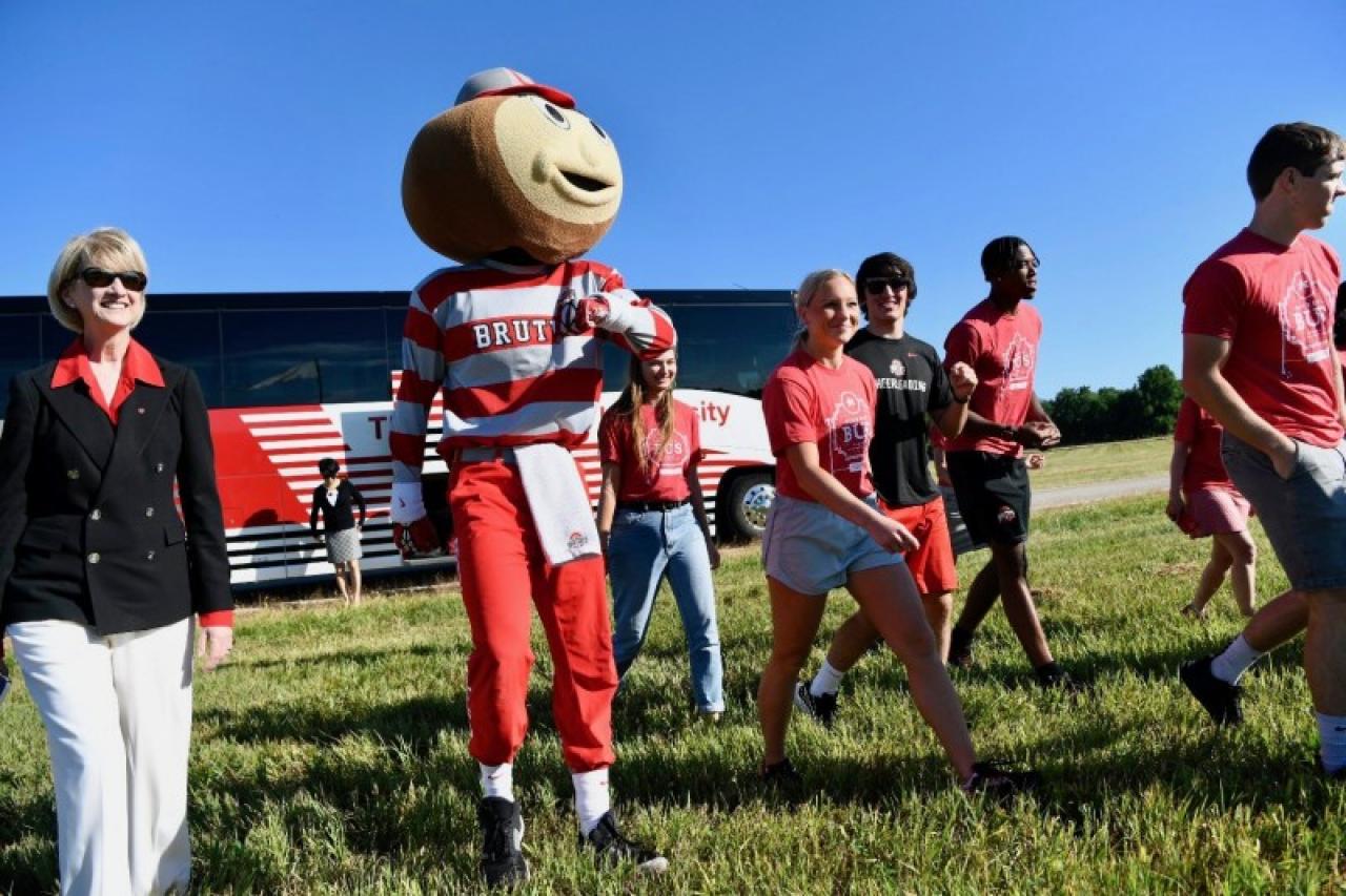 President Johnson, Brutus and students walking in front of the Buckeye Bus