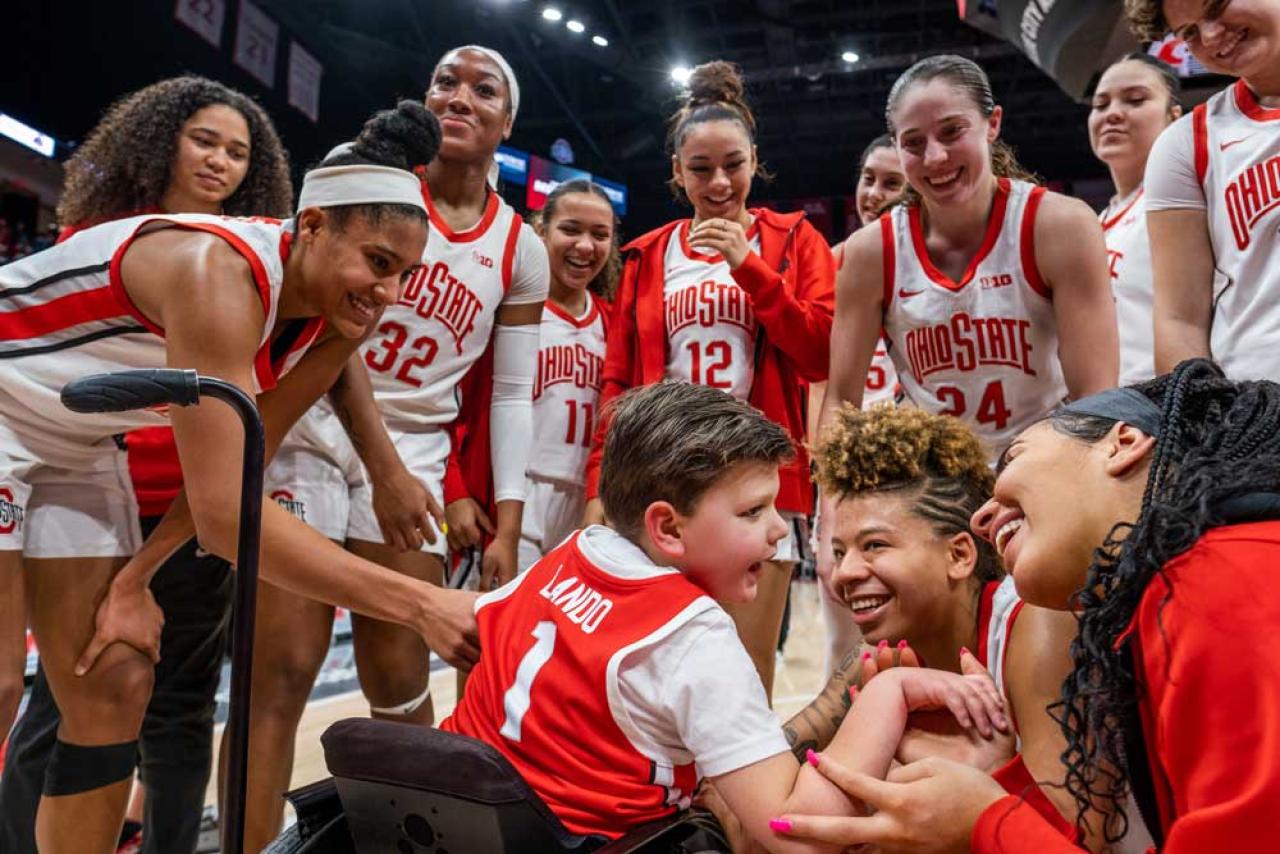 Members of the Ohio State women's basketball team crowded around a young fan in a wheelchair