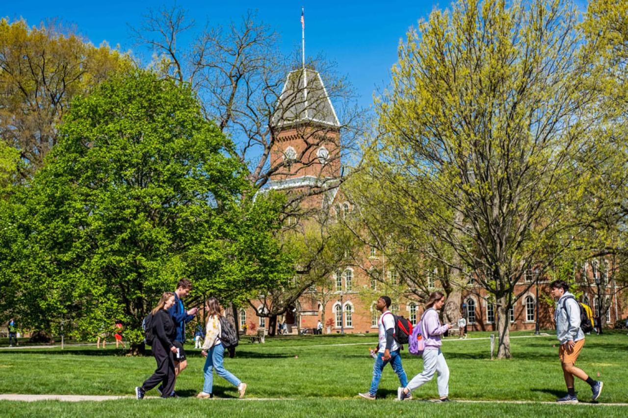 Students walking across the Oval on a bright spring day; University Hall is in the background