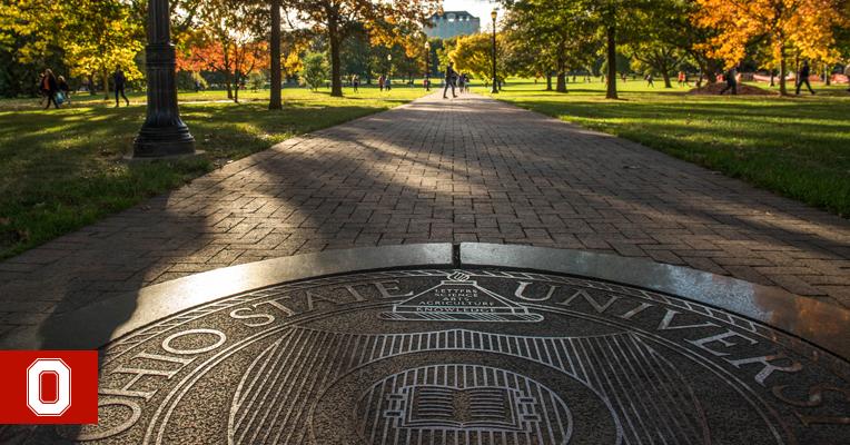 The Ohio State seal in the sidewalk on the Oval on a fall day