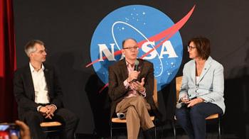 Three panelists seated on stage have a discussion.