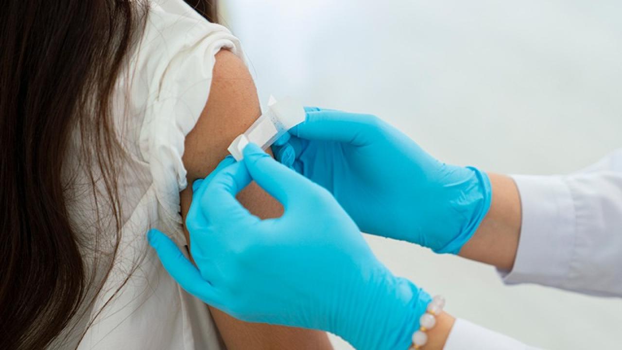 A band-aid being applied to a patient's upper arm