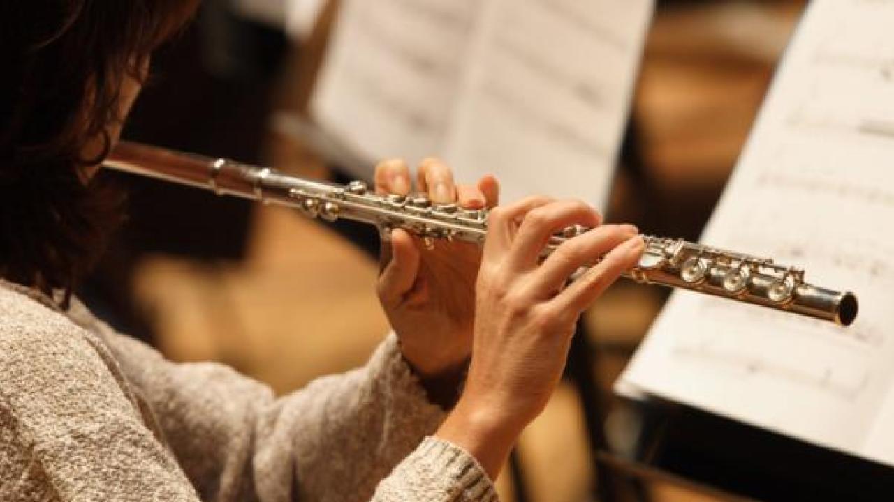 A musician reading sheet music as they play the flute