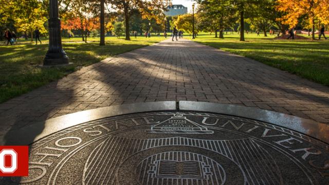 The Ohio State seal in the sidewalk on the Oval on a fall day